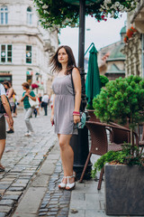 Young woman in summer dress downtown on flowers background. Woman in old town. The girl is walking in a beautiful old city