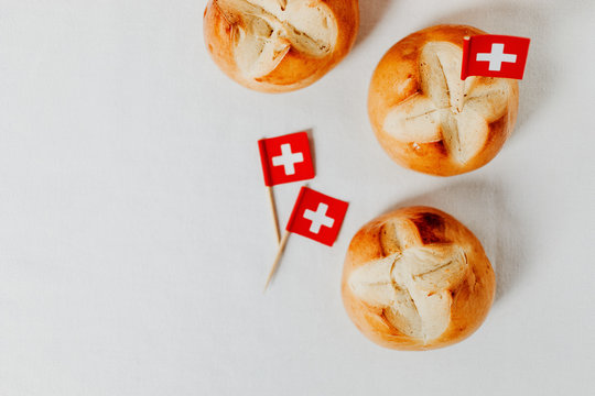 Swiss bread buns baked in Switzerland to celebrate Swiss National Day on August 1st. Swiss flag with white cross on red background.  
