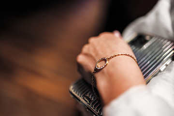 gold bracelet in the form of a ring with diamonds on a chain, girl’s hand, sleeve of a white shirt, dark background.
 - obrazy, fototapety, plakaty