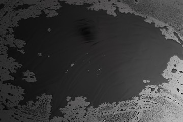 drops of water are sprayed on a black reflective glass