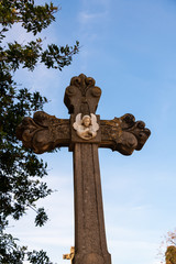 schönes Steinkreuz mit einem kleinen Engel auf einem Friedhof in Spanien
