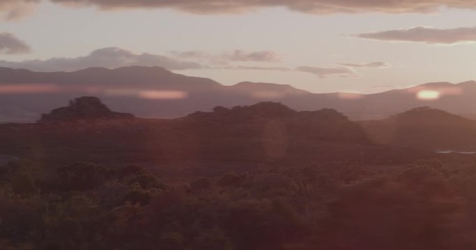 Tracking shot on empty mountain road in Sunrise with flare blinking through.