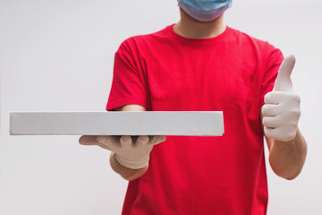 Man from delivery service in red t-shirt, wearing protective mask and gloves holding pizza box