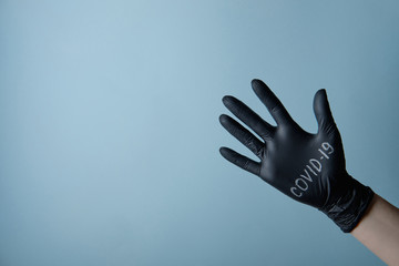 Symbol of coronavirus, girl in black gloves with the inscription, on a blue background