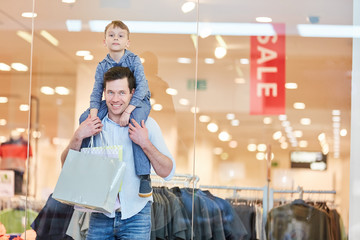 Mann mit Sohn im Huckepack beim Einkaufen