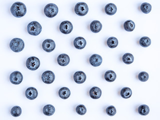 Looking down at blueberries laid out in a geometric pattern on a white background 