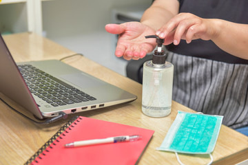  Woman washing hand with Alcohol Sanitizer before starting to work at home to prevent the spread of...