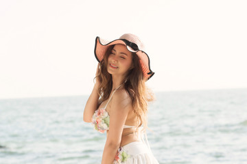 Portrait of smiling beautiful young woman wearing summer hat with large brim at beach.