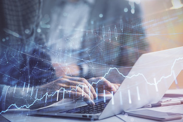 Double exposure of market chart with man working on computer on background. Concept of financial analysis.