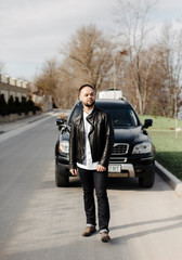 Portrait of fashionable well dressed man with beard posing outdoors