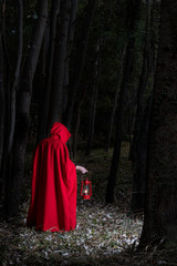 Attractive woman dressed a little red riding-hood walk in a dark forest with lantern - 338331798