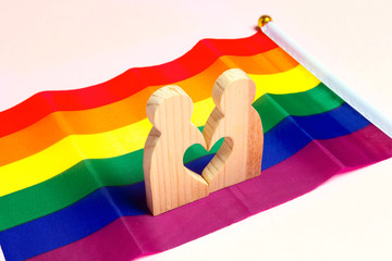 LGBT couple wooden figures on rainbow flag.