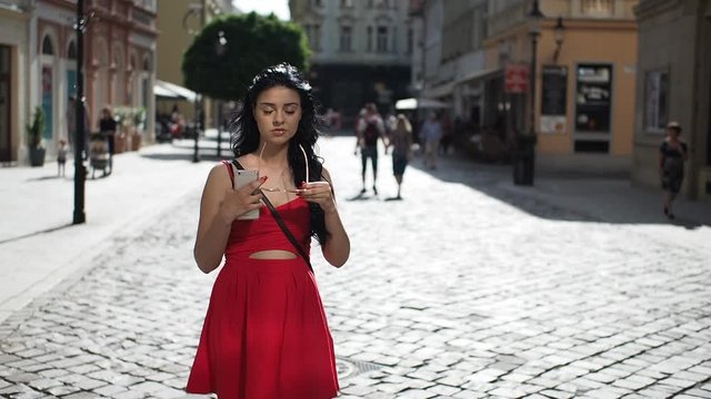 Young brunette woman with sunglasses standing on the street, looking around and enjoying free time in historical part of Bratislava city in SLOW MOTION HD VIDEO. Half speed, front view.