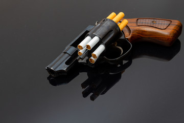 Dangerous revolver with cigarettes as bullets on shiny surface