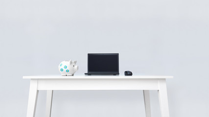 Clean white office desk with piggy bank and desktop computer.