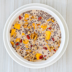 Granola with yellow mango, red goji berries and almond milk, closeup