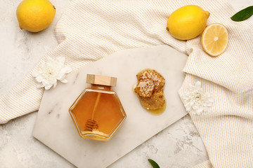 Jar of sweet honey with lemon on white background