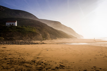 Fototapeta na wymiar Sandy beach near green hills at sunset