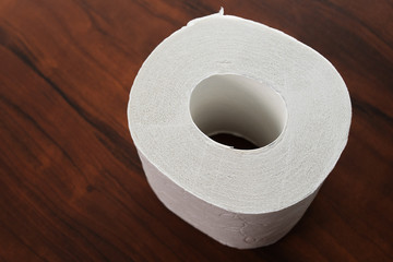 Roll of white toilet paper on a wooden background