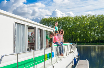Fototapeta premium Family vacation, summer holiday travel on barge boat in canal, happy kids and parents having fun on river cruise trip in houseboat in France 