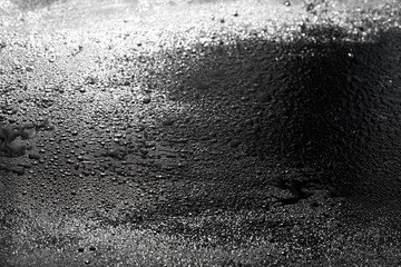 drops of water are sprayed on a black reflective glass