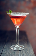 Red cocktail with bloody oranges in martini glass on the rustic background. Selective focus. Shallow depth of field.