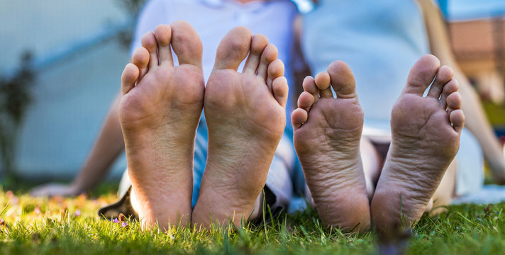 Romantic young couple kissing in the garden. Family feet in focus. Feet of a young couple lying on grass at the park.