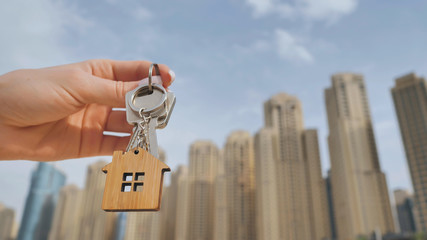 Real estate purchase concept. The girl holds the keys to a new house on the background of a Dubai...