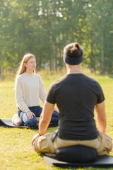 A group of young people meditate outdoors in a park. 