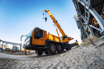 A large yellow truck crane stands ready to work on the construction site