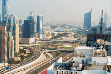 Highway road interchange or junction with urban car traffic and Dubai skyline with high tower buildings, UAE, view from above.