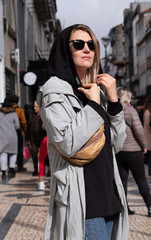 A beautiful stylish woman in dark glasses stands on a beautiful European street