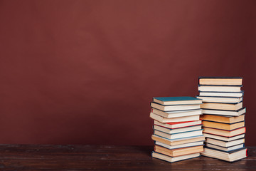 many stacks of educational books to study in the university library on a brown background