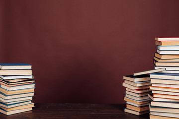 many stacks of educational books to study in the university library on a brown background