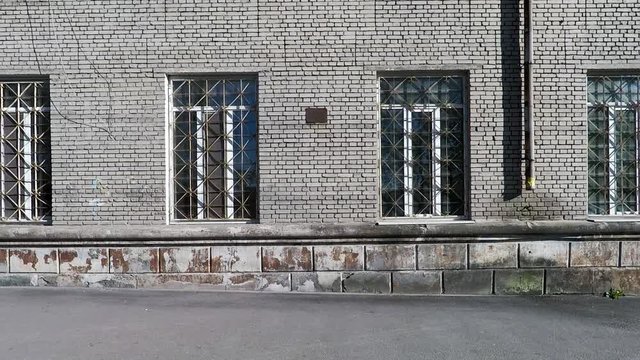 background texture wall of the facade of an old building made of brick with windows and bars, imitation blocks with old peeled paint