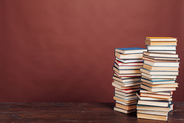 many stacks of educational books to study in the university library on a brown background