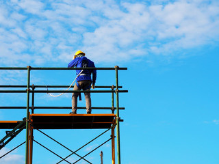 Man Working on the Working at height on construction site with blue sky