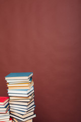 many stacks of educational books to study in the university library on a brown background