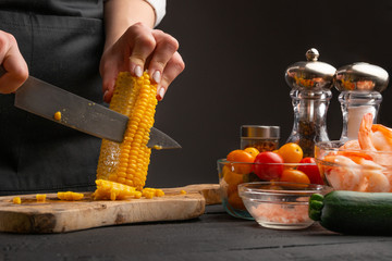 the chef cuts corn grains to prepare seafood dishes. Vegetables and proper nutrition. Recipe book....