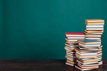 many stacks of educational books to teach in the school library on a green background