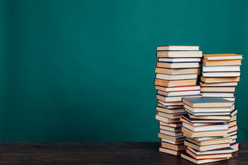 many stacks of educational books to teach in the school library on a green background