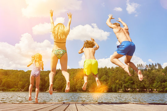 Familie springt in Wasser von See im Sommer