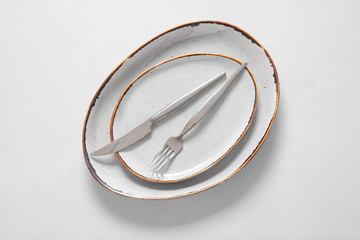 Clean plates and cutlery on light background