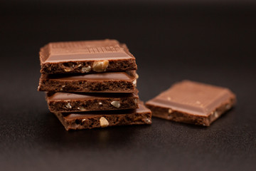 Pieces of chocolate with nuts on a dark background. Broken chocolate.