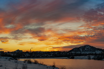 The colorful sky at sunset on a clear day plays with several colors , contrasting and rich beautiful view of the glow near the mountain and the city in winter