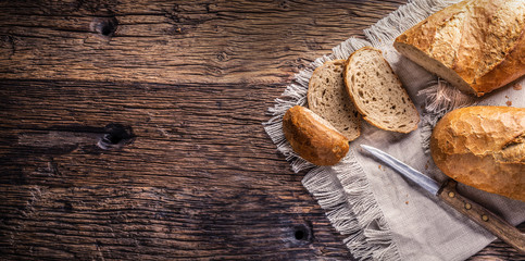 Banner view of two slices of crisp baked bread on a vintage cloth and wooden background with a knife on the side