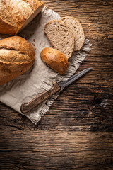 Plakat Top view of three slices of crisp baked bread on a vintage cloth and wooden background with a knife on the side