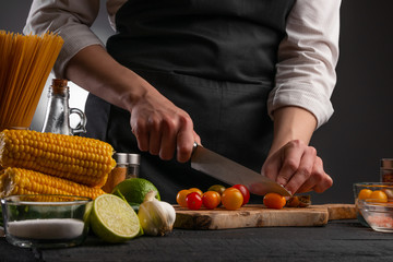 The chef cuts cherry tomatoes to make a fresh salad with shrimp, seafood. Cookery and recipe book. Restaurant cuisine. Recipes