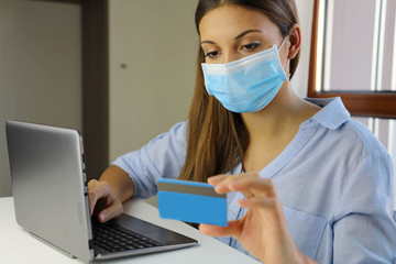 COVID-19 Pandemic Coronavirus E-commerce Mask Girl Buying with Laptop. Young woman with mask buying...