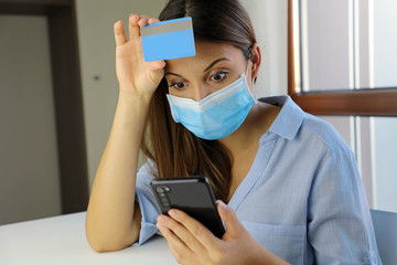 Global Economic Crisis Covid-19 Pandemic Coronavirus. Shocked desperate business woman with surgical mask looking on mobile phone her credit card statement stressed.